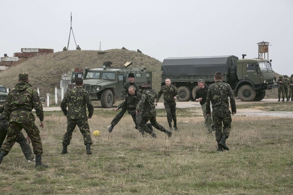 Ukrainische Soldaten vertreiben beim Flugplatz Belbek vertreiben sich die Zeit mit Fussball spielen. Im Hintergrund stehen russische Militärfahrzeuge.