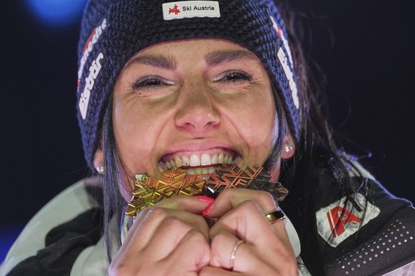 Austria&#039;s Stephanie Venier bites her gold medal for a women&#039;s Super-G, left, and her bronze medal for a women&#039;s team combined event, at the Alpine Ski World Championships, in Saalbach-H ...