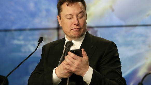 FILE - Elon Musk founder, CEO, and chief engineer/designer of SpaceX jokes with reporters as he pretends to search for an answer to a question on a cell phone during a news conference after a Falcon 9 ...