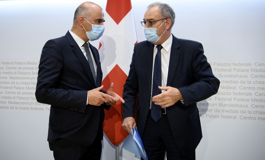 Bundesrat Alain Berset, links, und Bundesratspraesident Guy Parmelin, rechts, sprechen waehrend einer Medienkonferenz ueber die neusten Entscheide des Bundesrates zur Coronavirus-Pandemie, am Freitag, ...