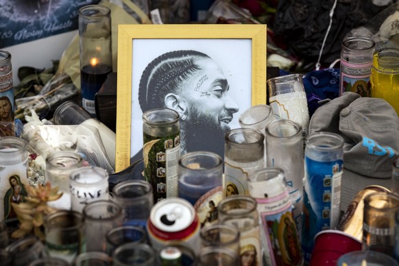 epa07481586 Candles and portraits of US rapper Nipsey Hussle sit on the ground where he was shot in Los Angeles, California, USA, 02 April 2019. On 01 April 2019, as people came to pay their respects  ...