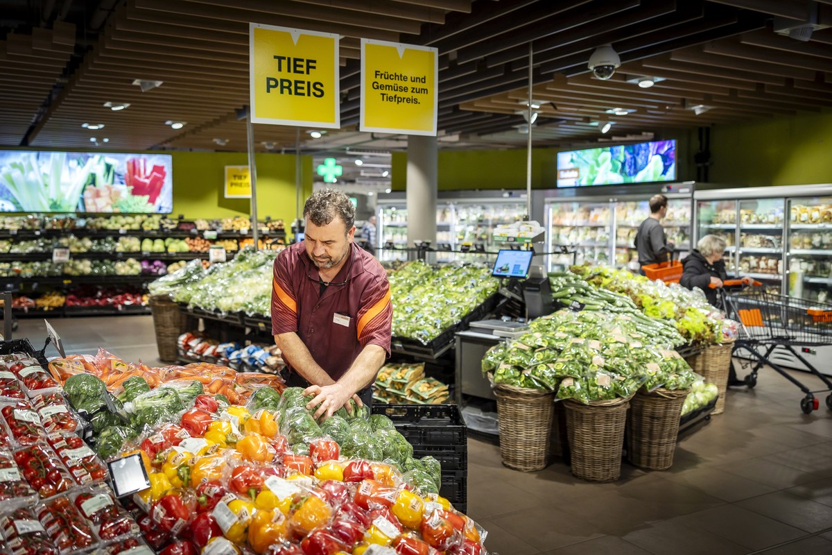 Ein Mitarbeiter raeumt Gemuese ein, neben einem Schild mit der Aufschrift "Tiefpreis" in der Migros Limmatplatz, aufgenommen anlaesslich einer Medienkonferenz zu Neuerungen in den Migros-Sup ...
