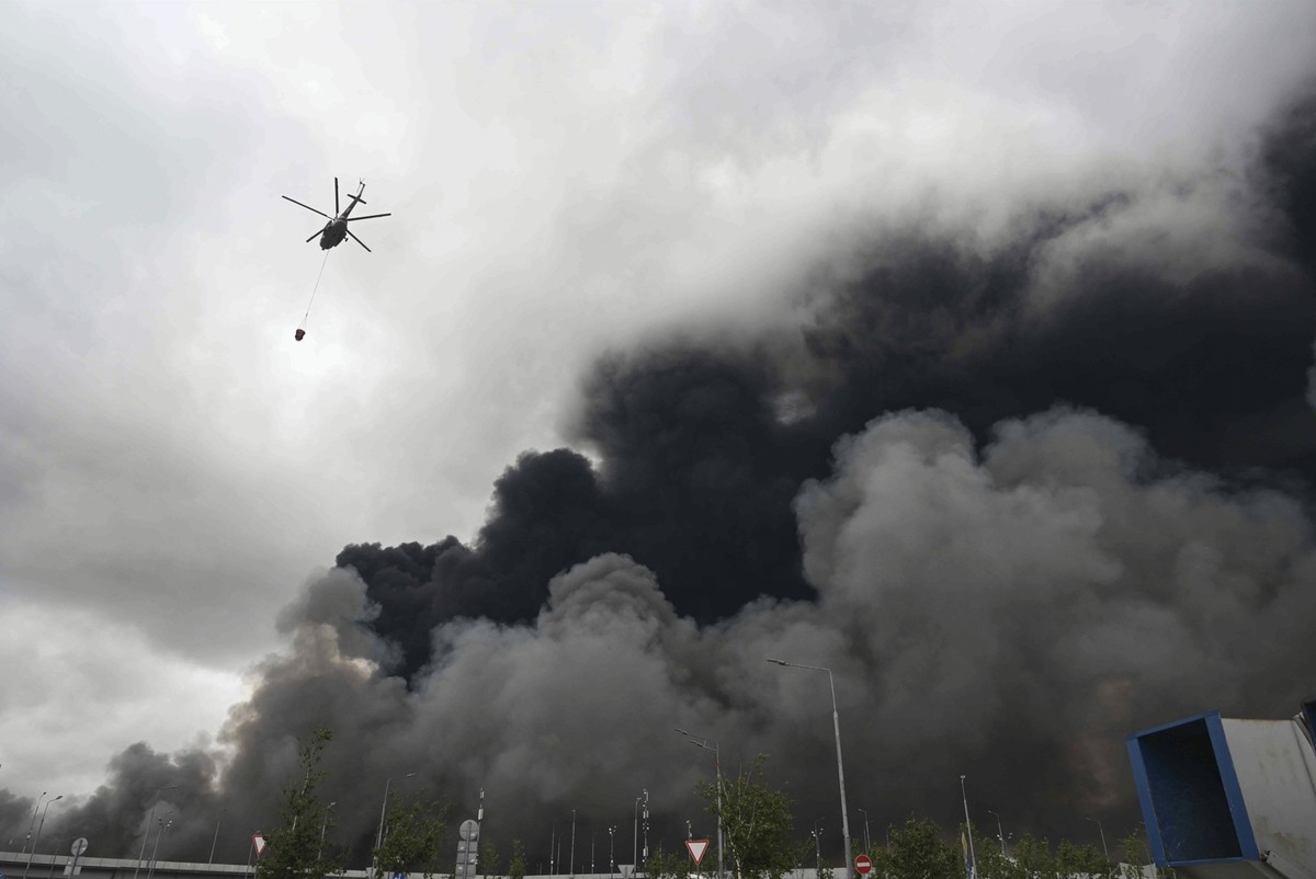 Ein Löschhelikopter ist nach einem ukrainischen Drohnenangriff im Einsatz, während schwarzer Rauch aus der Ölraffinerie Gazprom Neft in Moskau aufsteigt, am 18. Juni 2026.