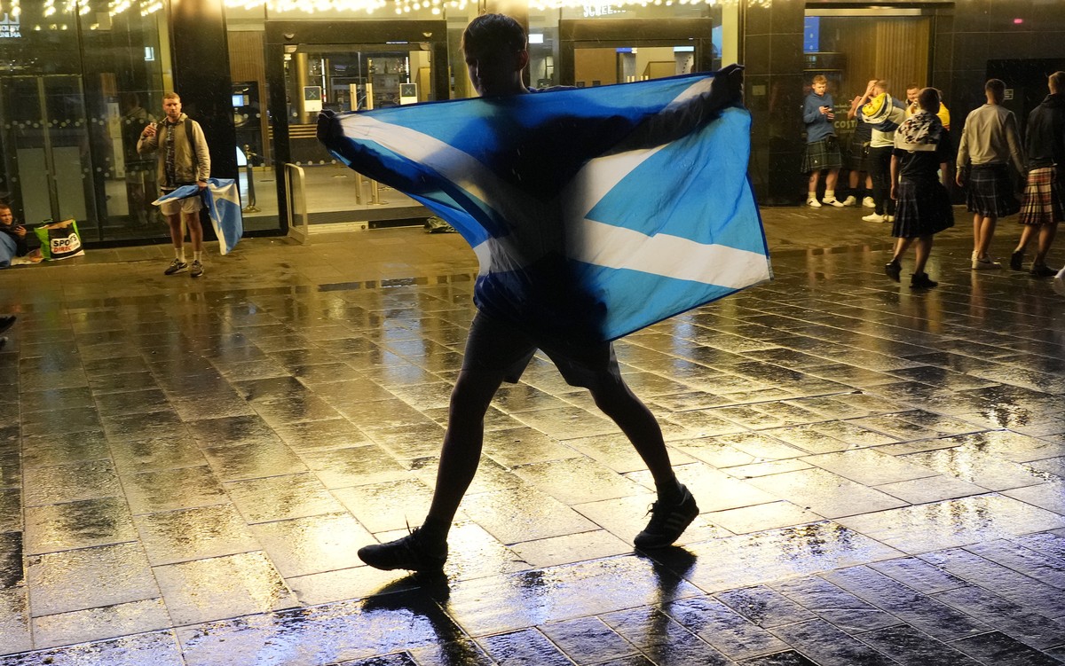 A Scotland supporter holds a flag as he walks through Leicester Square in London, Friday, June 18, 2021 after the Euro 2020 soccer championship group D match between England and Scotland at Wembley St ...
