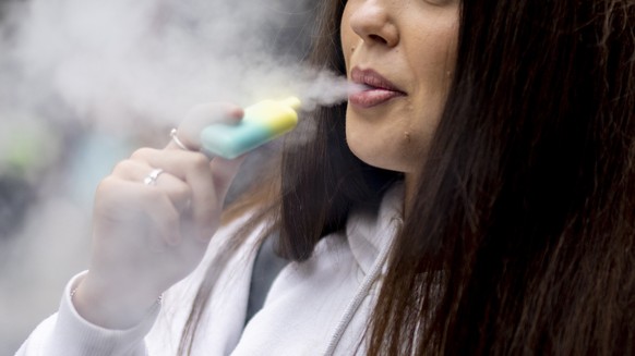 epa10663273 A person uses a single-use vaping product in London, Britain, 30 May 2023. The UK government has announced it is cracking down on retailers providing free vape samples to children. The gov ...