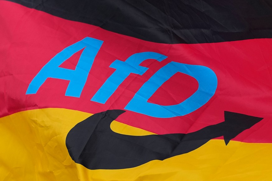 The logo of the "Alternative for Germany" (AfD) party is fixed on a German national flag for the state elections in Saxony-Anhalt during an election campaign event in Magdeburg, Germany, Fri ...