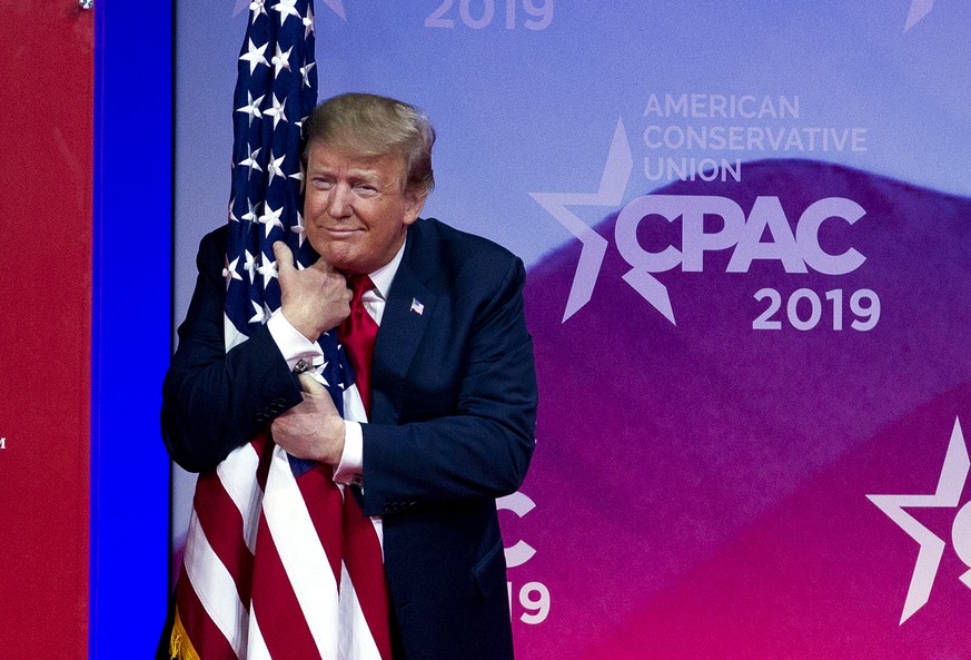 President Donald Trump hugs the American flag as he arrives to speak at Conservative Political Action Conference, CPAC 2019, in Oxon Hill, Md., Saturday, March 2, 2019. (AP Photo/Jose Luis Magana)