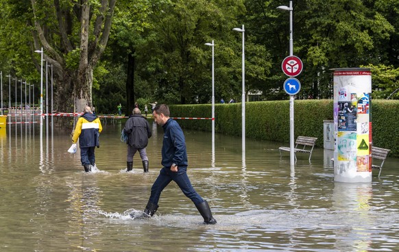 epa09348753 People walk in the lake water in the harbor as the water level of the Bielersee rose following heavy rainfall over the past few days in Biel, Switzerland, 16 July 2021. The water level of  ...