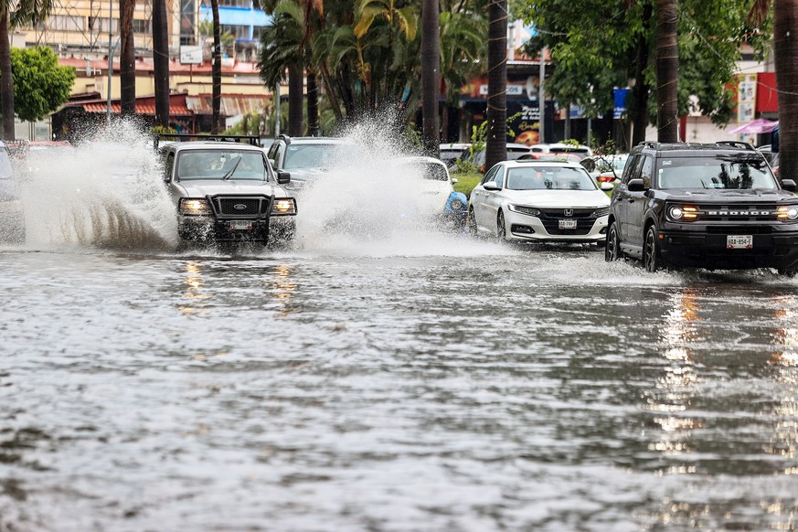 epa10803595 Cars move on a flooded street due to heavy rains in the resort of Acapulco, Guerrero state, Mexico, 16 August 2023. Mexico expects tropical storm Hilary, the eighth named cyclone of the se ...