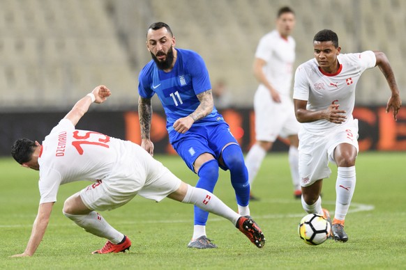 Greece&#039;s forward Kostas Mitroglou, center, fights for the ball with Switzerland&#039;s defender Manuel Akanji, right, and Switzerland&#039;s midfielder Blerim Dzemaili, left, during an internatio ...