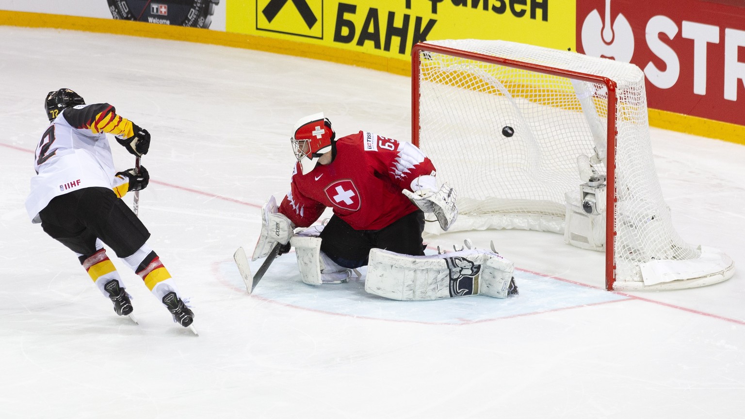 epa09245586 Germany&#039;s Dominik Kahun (L) scores a penalty against Swiss goalie Leonardo Genoni (R) during the shootout of the IIHF Ice Hockey World Championship 2021 quarter final game between Swi ...