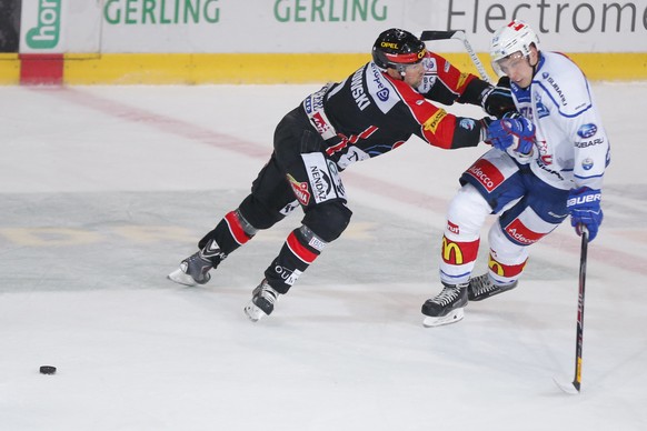Le joueur fribourgeois Joel Kwiatkowski, gauche, lutte pour le puck contre le joueur zurichois Mike Kuenzle, a droite, lors du match du championnat suisse de hockey sur glace de National League A, ent ...