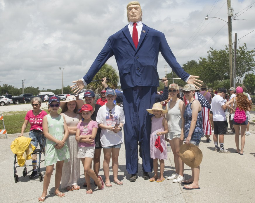 epa09321783 A family poses for a photo with a giant-size model of Donald J. Trump as people get ready to enter a rally hosted by former US President Donald J. Trump at the Sarasota County Fairgrounds  ...