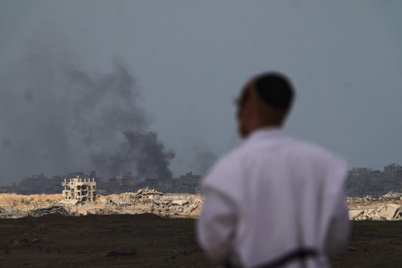 A Jewish man watches smoke rise in the sky after an explosion in the Gaza Strip, as seen from southern Israel, Thursday, Oct. 9, 2025, following the announcement that Israel and Hamas have agreed to t ...