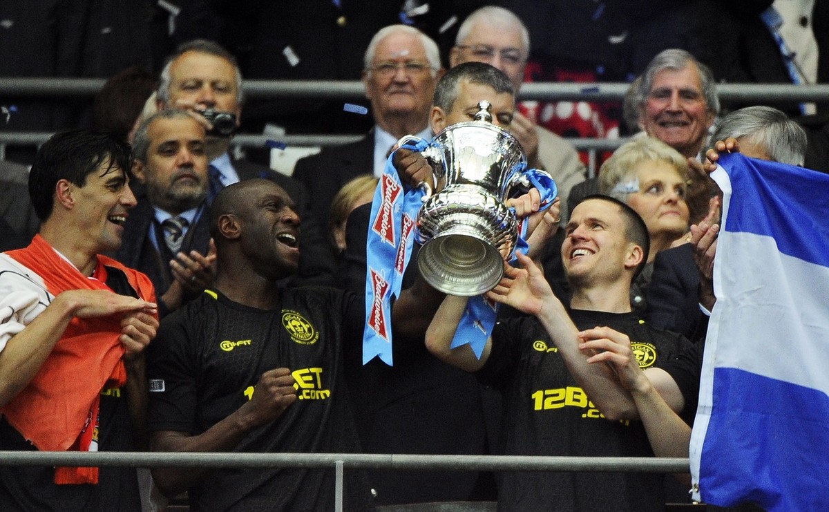 epa03696600 Wigan Athletic's (L-R) Paul Scharner, Emmerson Boyce and captain Gary Caldwell lift the trophy after winning the English FA Cup final soccer match between Manchester City and Wigan At ...