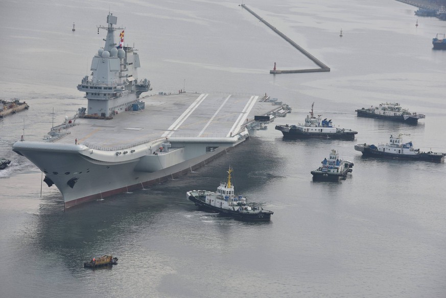 DALIAN, CHINA - AUGUST 26: China s first home-built aircraft carrier, towed by several towboats, sets for sea trial at Dalian shipyard on August 26, 2018 in Dalian, Liaoning Province of China. China s ...