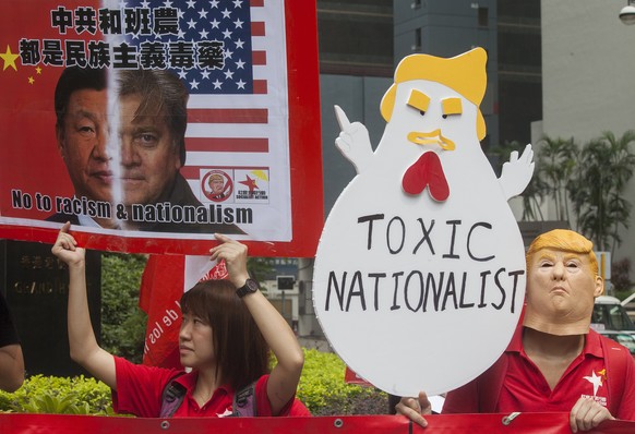 epa06199251 Anti-Steve Bannon protestors, one of them wearing a Trump mask (R), hold placards outside the venue of the &#039;Credit Lyonnais Securities Asia&#039; (CLSA) Investors Forum 2017, where US ...