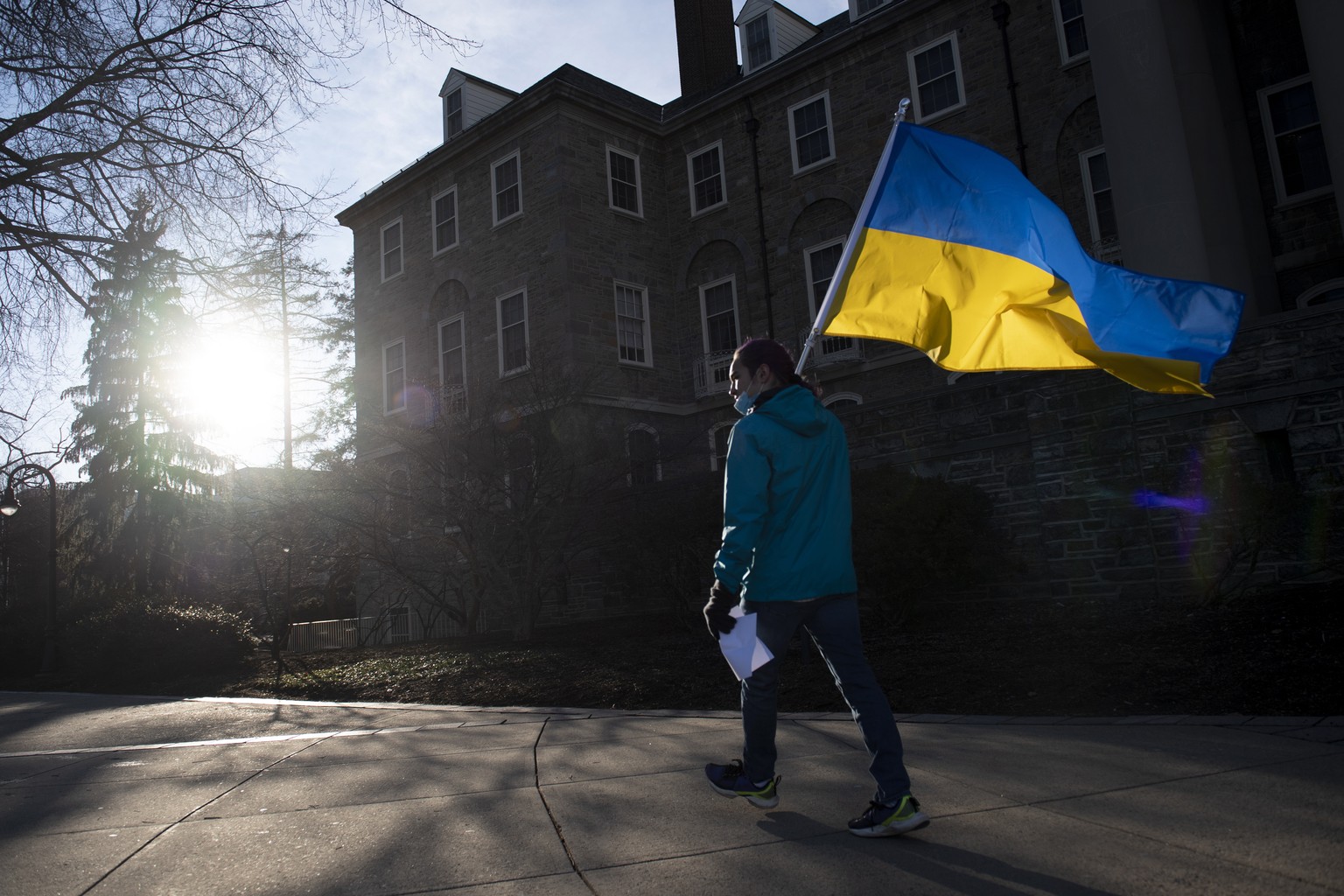 James Shin, of State College, holds a Ukrainian flag during an anti-war protest hosted by the Ukrainian Society at Penn State in front of Old Main on Thursday, March 3, 2022, in University Park, Pa. ( ...