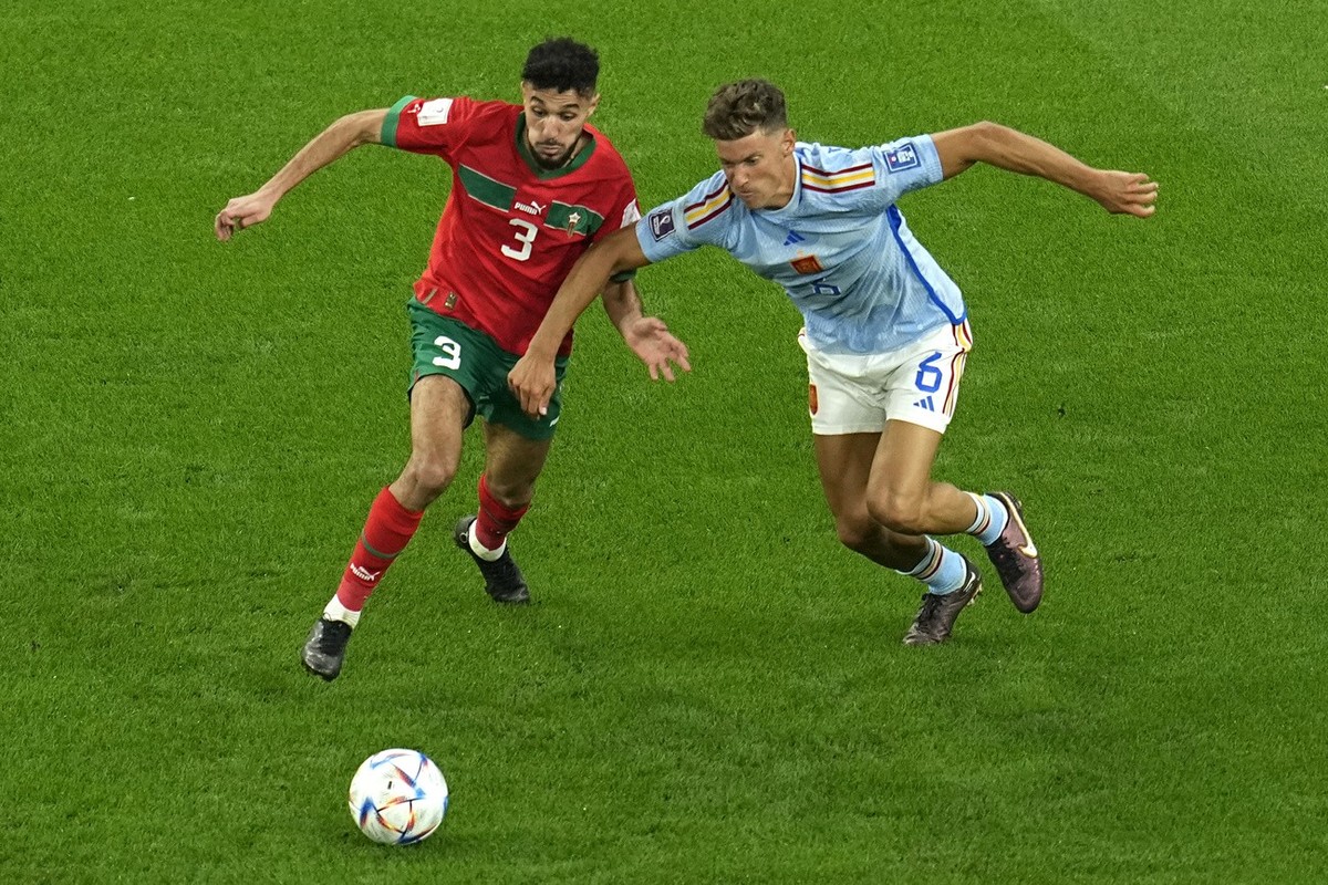 Morocco's Noussair Mazraoui, left, challenges for the ball with Spain's Marcos Llorente during the World Cup round of 16 soccer match between Morocco and Spain, at the Education City Stadium ...
