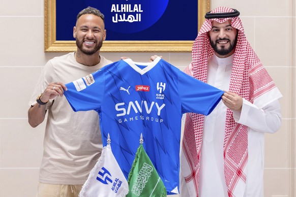 In this photo provided by the Al-Hilal Club Media Center, Neymar holds the Al-Hilal shirt after signing with the Chairman of the Board of Directors of Al-Hilal, Fahd bin Saad bin Nafel, in Paris, France, Tuesday, ...