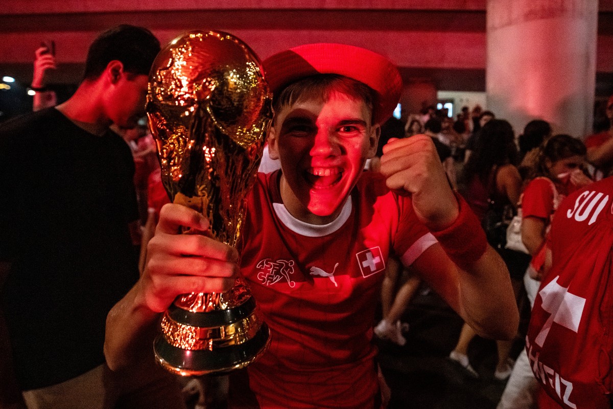 A fan of team Switzerland poses with a replica of the World Cup trophy as the Swiss fans gather on the streets arround a trainstation after Switzerland won the 2026 FIFA World Cup soccer round of 16 s ...