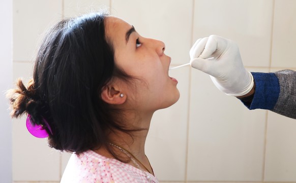 epa09896915 A woman undergoes a swab test to detect Covid-19 at CV Raman government hospital in Bangalore, India, 19 April 2022. The daily Covid-19 active cases have been rising in India since late Ja ...