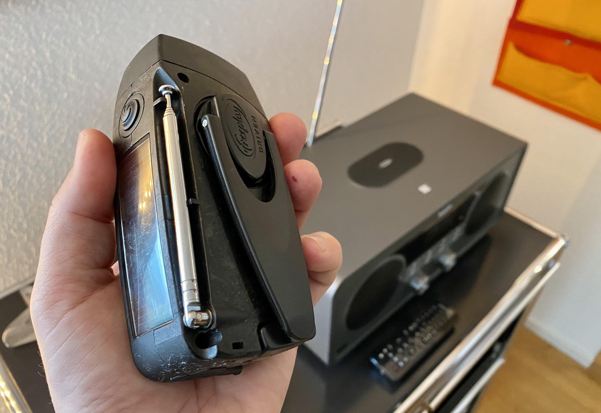 Mit Solarenergie und Kurbel aufladbares UKW-Taschenradio, im Hintergrund ein modernes Digitalradio (DAB+), das über die Antenne auch UKW-Wellen empfängt.