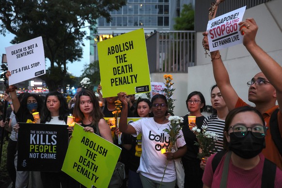 epa11907075 Human rights activists hold flowers, placards and candles during a candlelight vigil to protest against the death penalty and upcoming execution of a Malaysian man in Singapore, outside Si ...