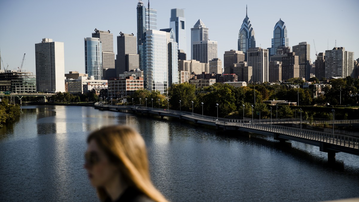 A woman crosses the South Street Bridge spanning the Schuylkill River and view of the Philadelphia skyline, Wednesday, Oct. 18, 2017. The cities of Philadelphia and Pittsburgh are both attempting to d ...