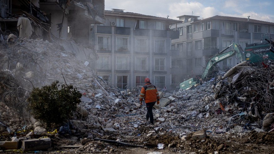 epa10478186 A rescuer walks on debris of collapsed buildings after a powerful earthquake, in Hatay, Turkey, 19 February 2023. More than 46,000 people have died and thousands more are injured after two ...
