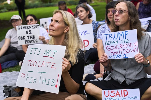 Layne Morrison, left, of Washington, and Courtney Creek, of Silver Spring, Md., who were let go from their jobs with the Education Department and a USAID funded grant respectively, hold signs about th ...