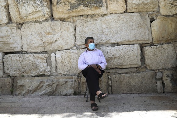 A Muslim man wears a protective face mask as he sits outside the Dome of the Rock and al-Aqsa mosque compound, which remains shut to prevent the spread of coronavirus in Jerusalem&#039;s Old City, Fri ...