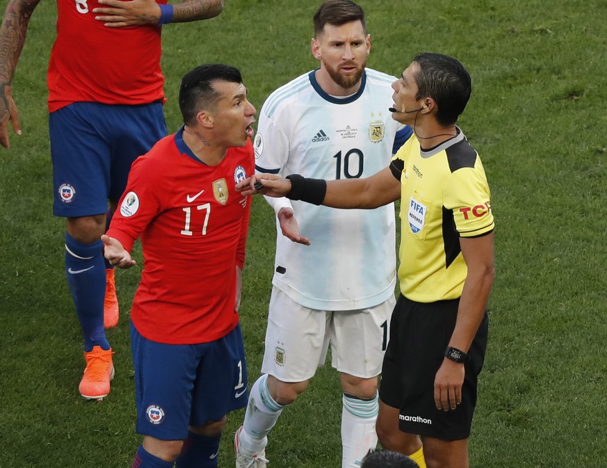 Chile&#039;s Gary Medel, left, and Argentina&#039;s Lionel Messi, center, protest to referee Mario Diaz after both of them receiving the red card during the Copa America third-place soccer match at th ...