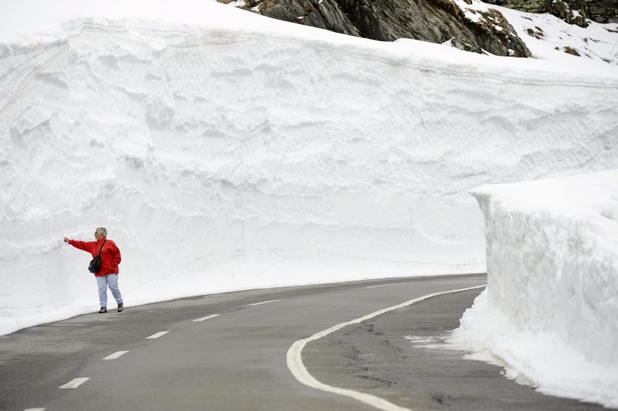 Eine Frau berührt die gigantische Schneewand auf dem Grossen Sankt Bernhard.