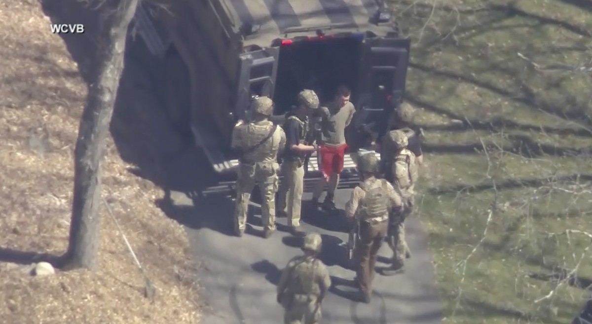 This image made from video provided by WCVB-TV, shows Jack Teixeira, in T-shirt and shorts, being taken into custody by armed tactical agents on Thursday, April 13, 2023, in Dighton, Mass. (WCVB-TV vi ...