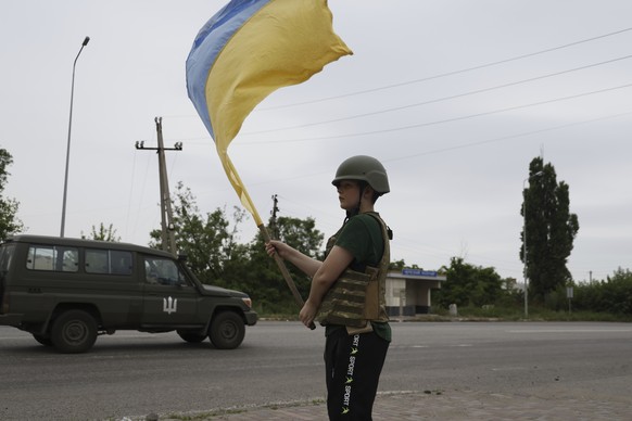Serhii Zinko, a twelve year-old boy, waves a national Ukrainian flag to a military car on the highway near Lyman, Ukraine, Monday, June 26, 2023. (AP Photo/Alex Babenko)