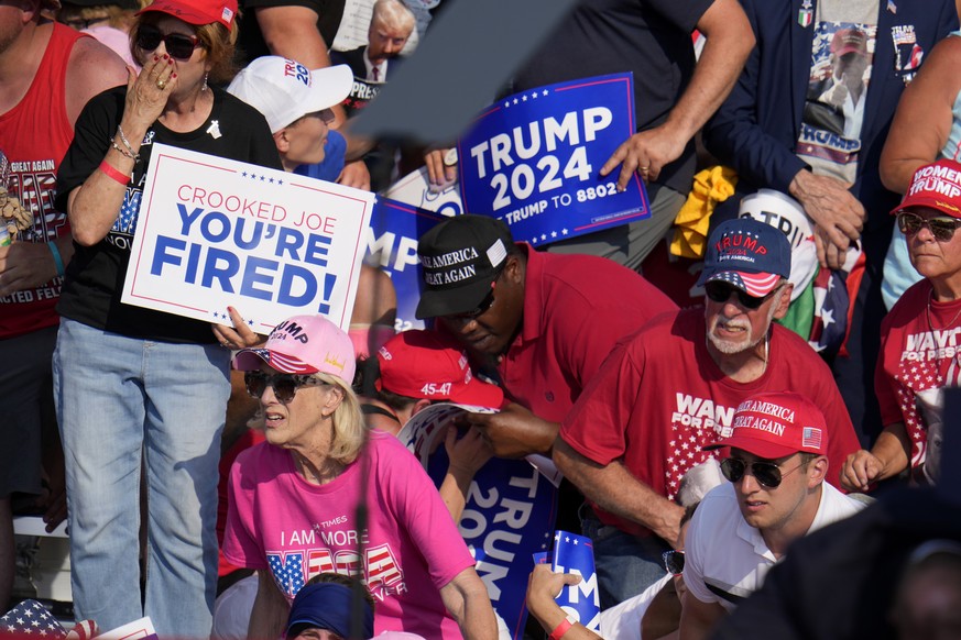 Members of the crowd react as U.S. Secret Service agents surround Republican presidential candidate former President Donald Trump at a campaign event in Butler, Pa., on Saturday, July 13, 2024. (AP Ph ...