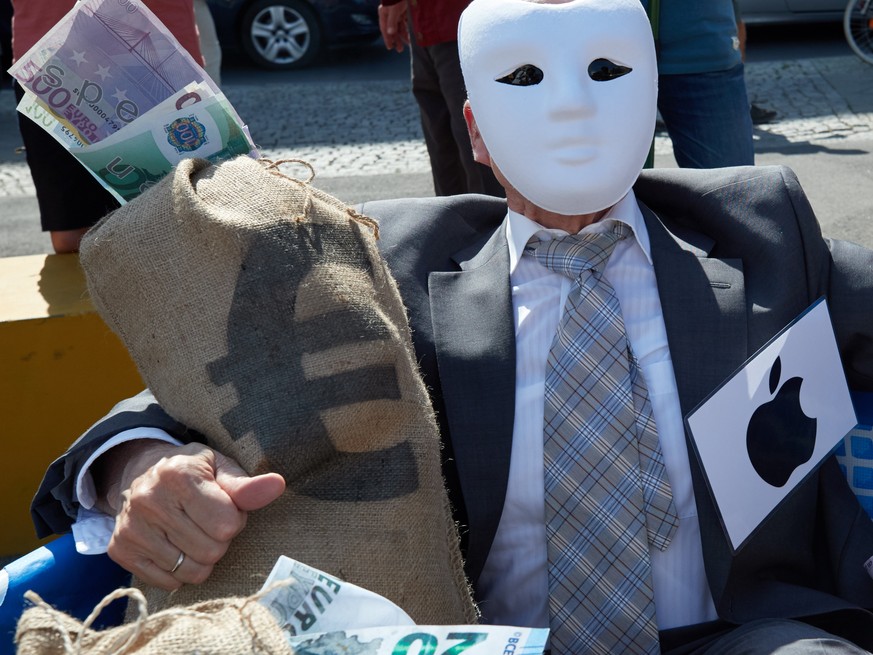 epa06760267 An activist from the nonprofit organization Campact representing Apple hugs a mock bag of money during a street performance in front of the Federal Ministry of Finance building in Berlin,  ...