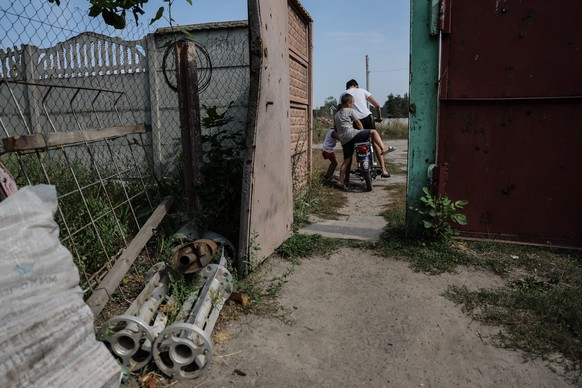 epa10833488 Children ride on the motorbike in the yard of their home which was damaged by Russian shelling and occupied by Russian soldiers in the village of Ruski Tyshky which is only 17 km&#039;s fr ...