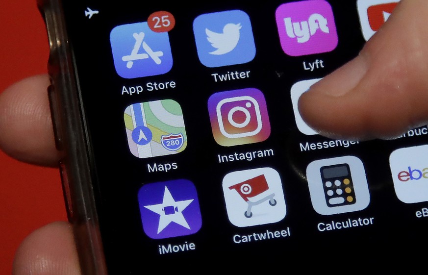 This July 10, 2019, photo shows an Associated Press reporter holding a phone showing the Instagram app icon in San Francisco. Instagram is expanding a test to hide how many ÄúlikesÄù peopleÄôs post ...