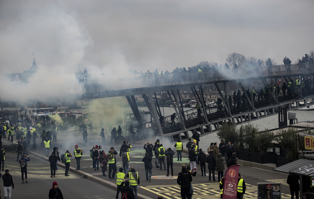 epa07264061 Protesters try to cross a bridge over the Seine river during a 'Yellow Vests' protest in Paris, France, 05 January 2019. The so-called 'gilets jaunes' (yellow vests) is ...