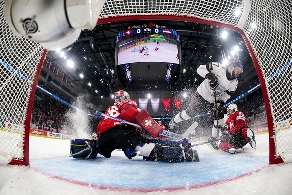 KEYPIX - From left: Switzerland's goaltender Sandro Aeschlimann, Latvia's Martins Dzierkals and Switzerland's Janis Moser fight for the puck during the 2026 IIHF Men's Ice Hockey W ...