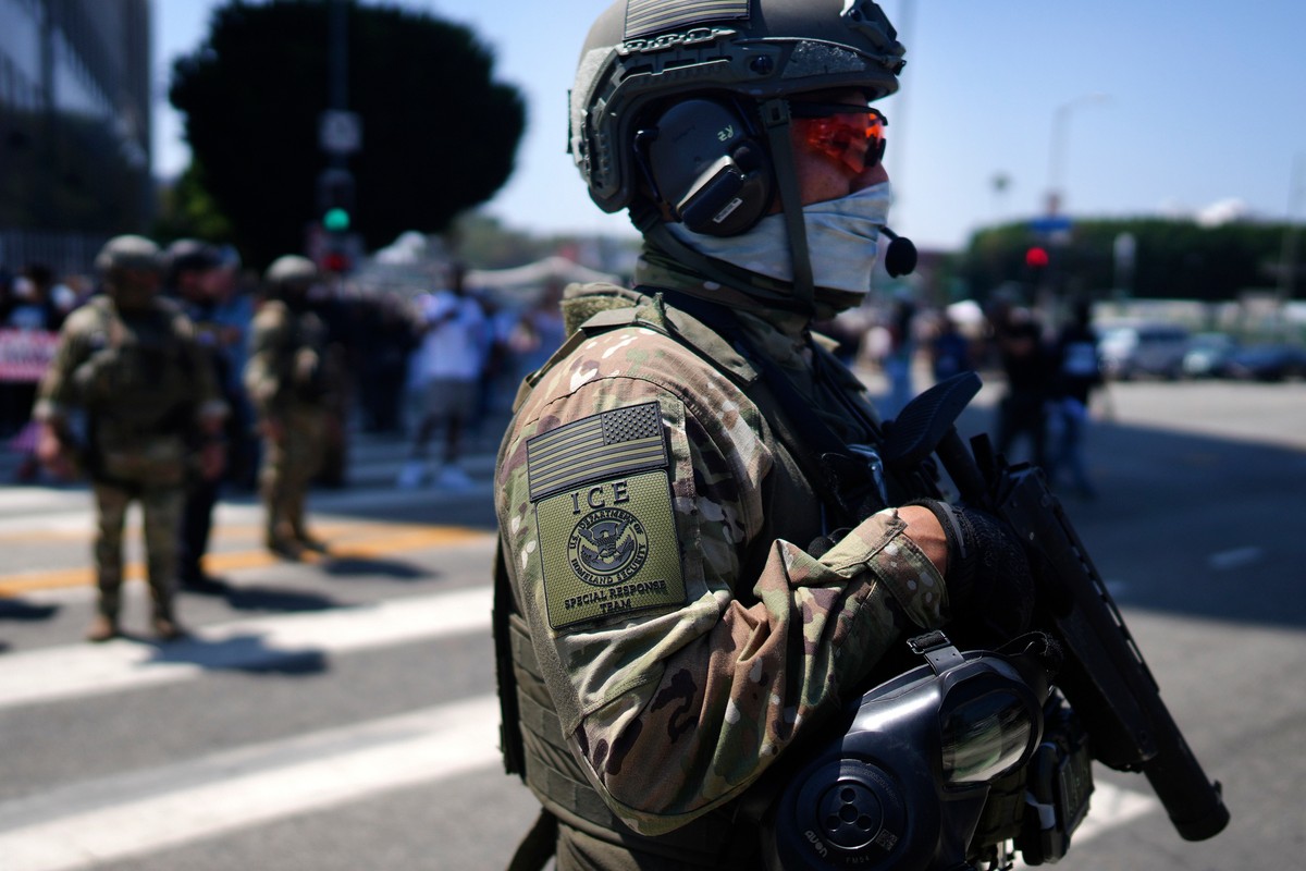 FILE - An ICE Special Response Team member stands guard outside the Metropolitan Detention Center, while protesters gather outside to denounce the ICE, U.S. Immigration and Customs Enforcement, operat ...