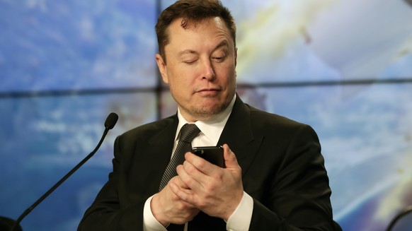 FILE - Elon Musk founder, CEO, and chief engineer/designer of SpaceX jokes with reporters as he pretends to search for an answer to a question on a cell phone during a news conference after a Falcon 9 ...