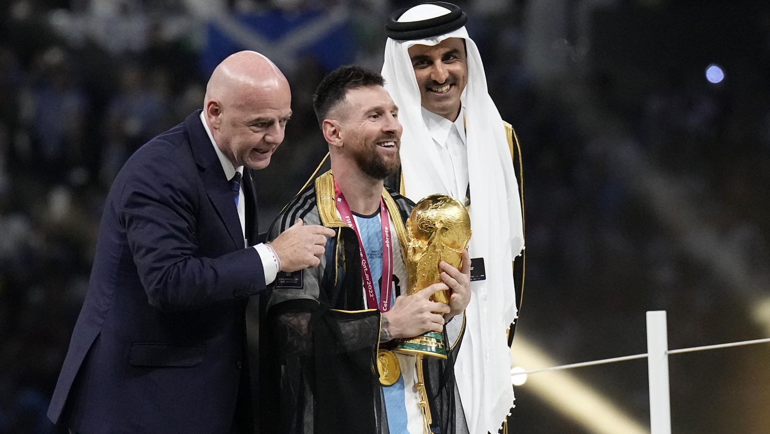 Argentina&#039;s Lionel Messi receives the trophy from FIFA President Gianni Infantino, left, and the Emir of Qatar Sheikh Tamim bin Hamad Al Thani, after winning the World Cup final soccer match betw ...