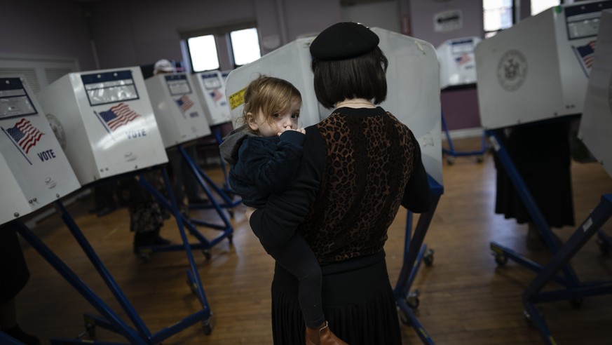 A member of the Orthodox Jewish community carries her child as she fills out ballot papers at a polling center on, Tuesday, Nov. 8, 2022, in the Brooklyn borough of New York. (AP Photo/Wong Maye-E)