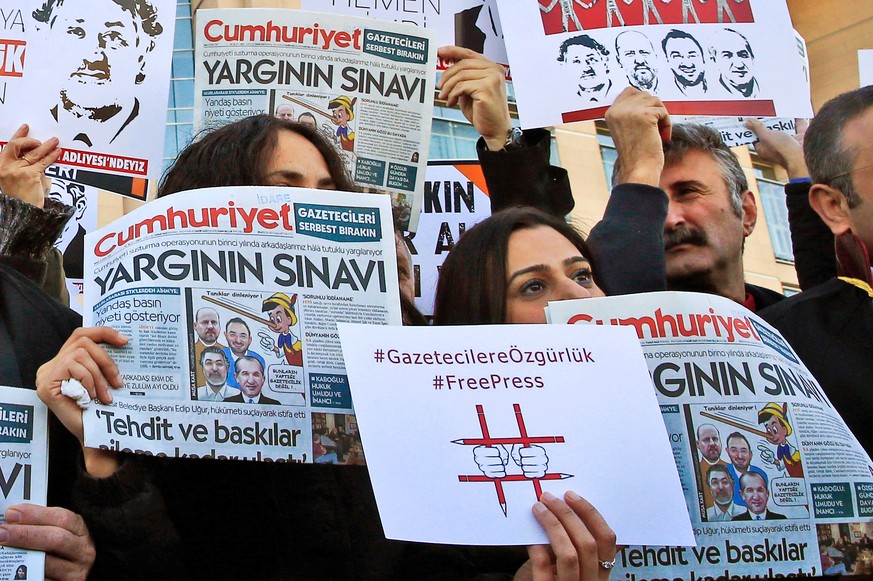 FILE - In this file photo dated Tuesday, Oct. 31, 2017, demonstrators hold placards and copies of the Cumhuriyet daily newspaper as they stage a protest outside a court where the trial of about a doze ...