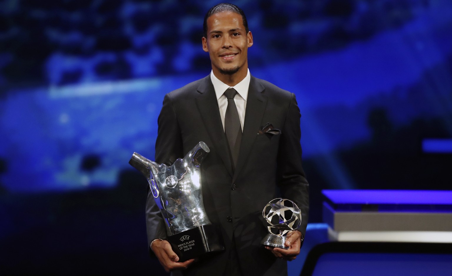 Dutch soccer player Virgil van Dijk of Liverpool holds the award of men's player of the year 2018/19 during the group stage draw at the Grimaldi Forum, in Monaco, Thursday, Aug. 29, 2019. (AP Photo/Da ...