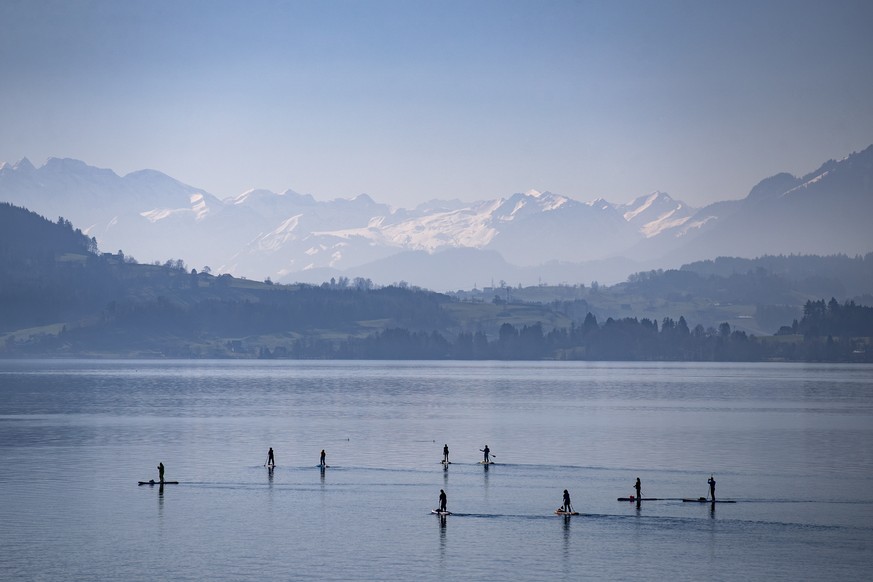 A group of stand up paddlers on the Lake of Zug on a sunny and mild Sunday, February 21 2021. In some regions of Switzerland the temperatures rose to 20 degrees. (KEYSTONE/Alexandra Wey)