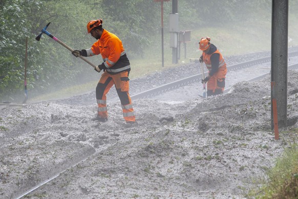 Arbeiter der SBB befreien die Gleise mit Schaufel und Pickel von der Hagelschicht, am Donnerstag, 24. Juni 2021 in Sonzeboz. Am Mittwochabend, 23. Juni 2021, kam es zu einem Unwetter mit starkem Hagel ...